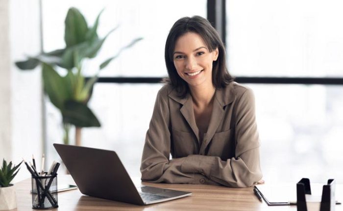 A smiling HR manager at her desk with a laptop